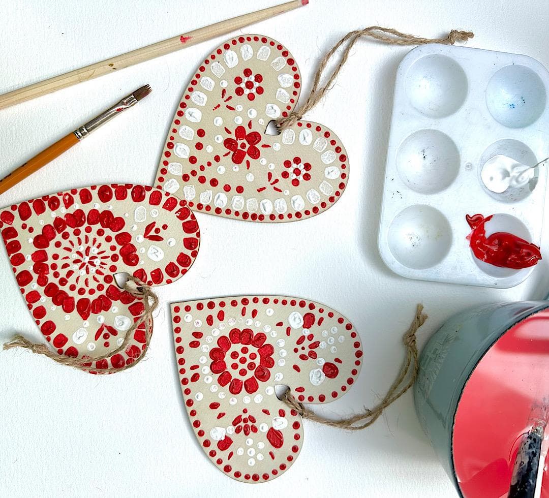 Painting Scandi-style wooden Christmas heart decorations in red and white